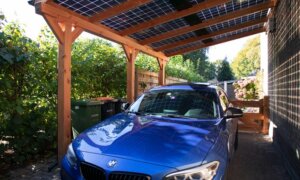 Blauwe auto onder houten carport met zonnepanelen